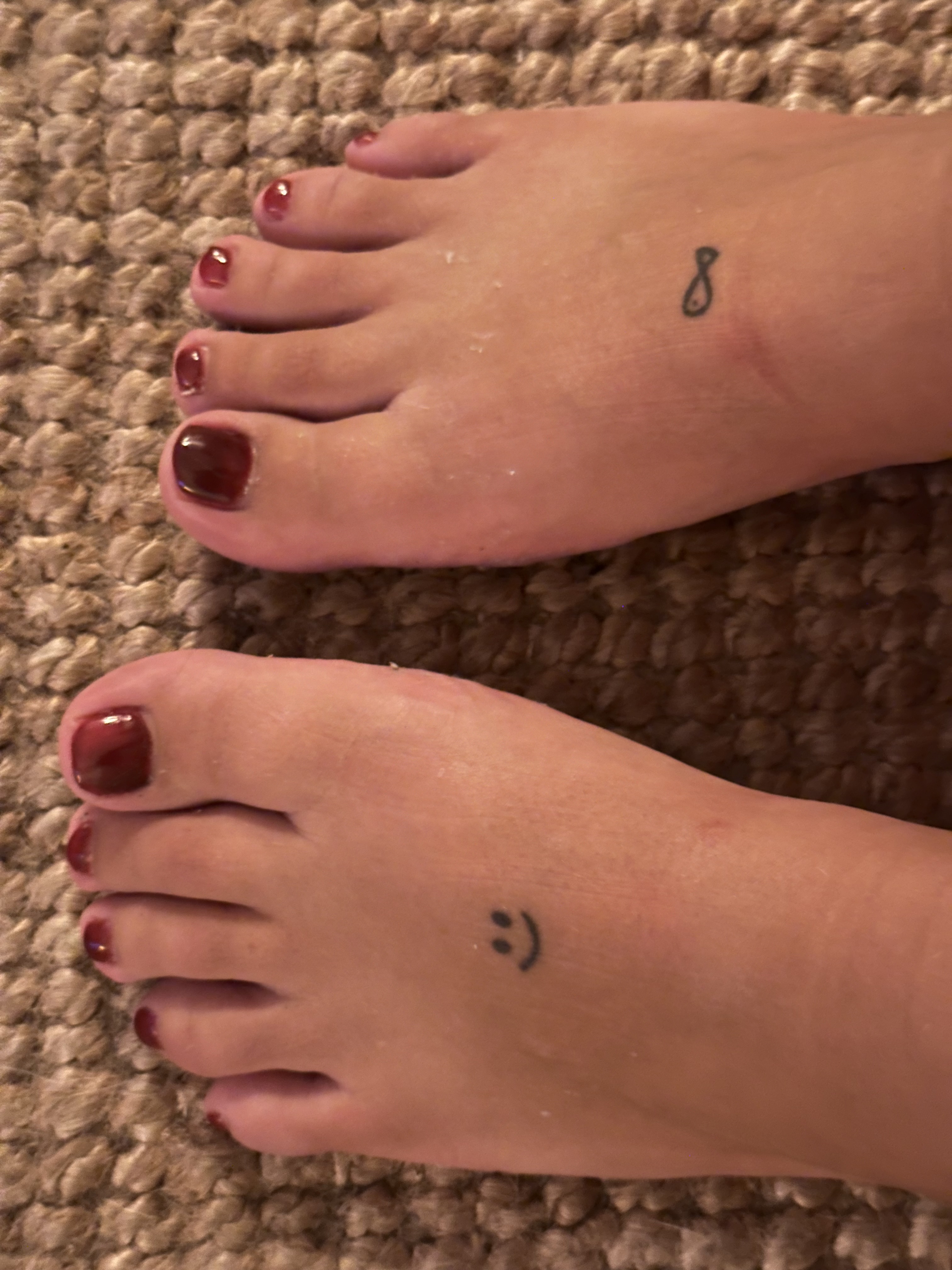 Robijnrode pedicure met smiley-tattoo